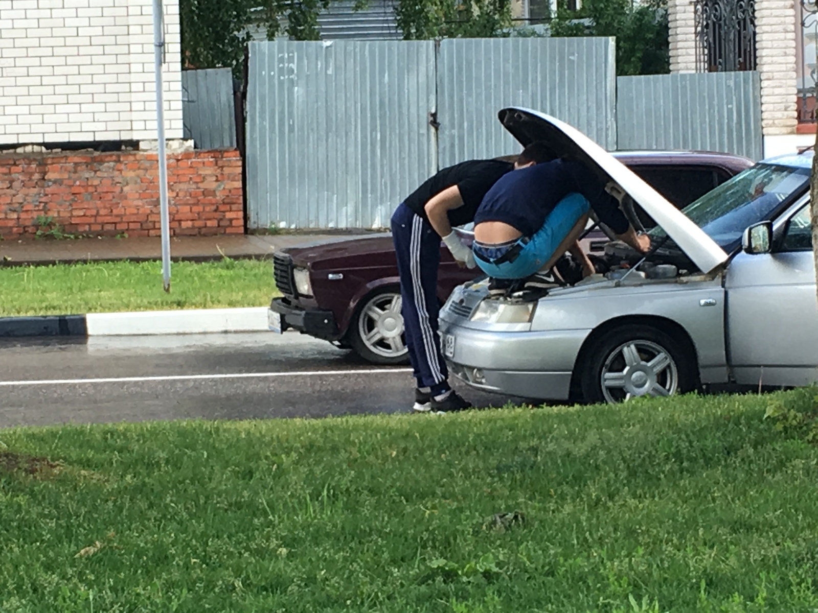 Мужчина ремонтирует машину во дворе